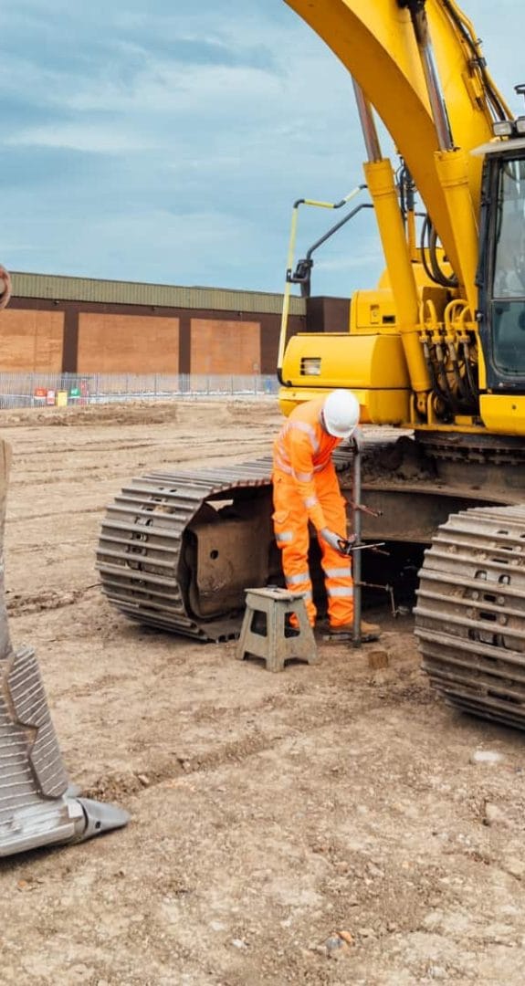 MATtest Site Services engineer carrying out soil characteristics and classification testing beside tracked excavator.