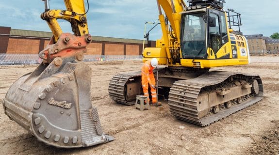MATtest Site Services engineer carrying out soil characteristics and classification testing beside tracked excavator.